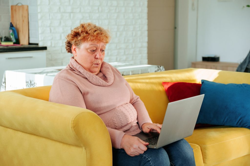 Surprised caucasian fat woman looking on laptop,