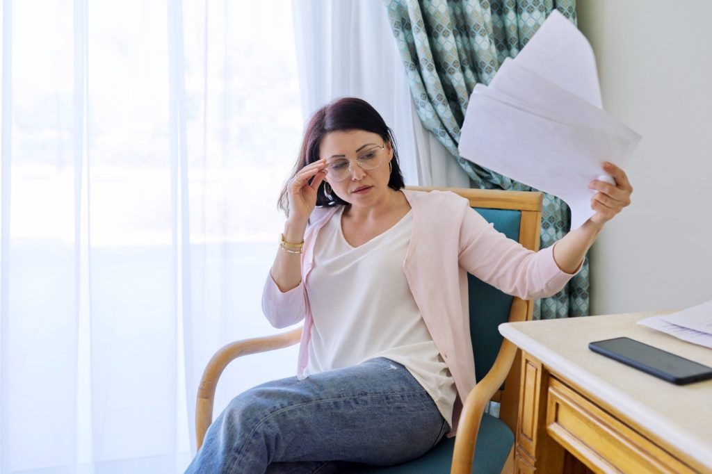 Mature woman waving papers, suffering from heat
